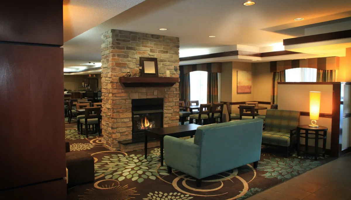 A cozy fireside seating area featuring a glowing fireplace, comfortable chairs, and a decorative rug. The inviting setup encourages relaxation and intimate conversation, perfect for couples seeking a romantic atmosphere indoors.